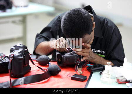 Dubai, United Arab Emirates, an employee of Canon Professional Service cleans an SLR Stock Photo