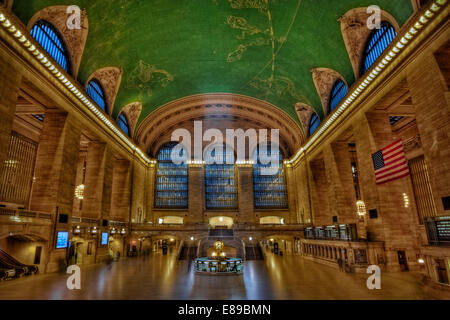 Grand Central Terminal - The main concourse of historic Grand Central Terminal in New York City. This view shows the entire concourse  including part of the beautiful depiction of the night sky painted across the ceiling, and the famous brass clock above the information booth. Grand Central Terminal, rebuilt in 1913, celebrated its 100th anniversary in 2013. Stock Photo