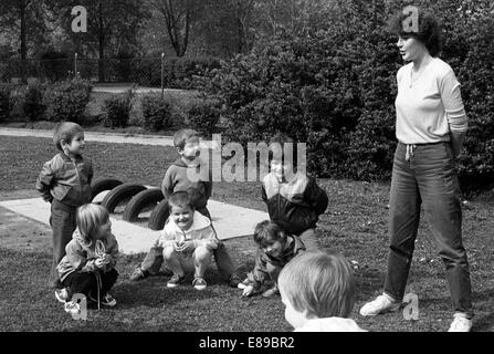 Berlin, DDR, kindergarten kids play with their educators outdoors Stock