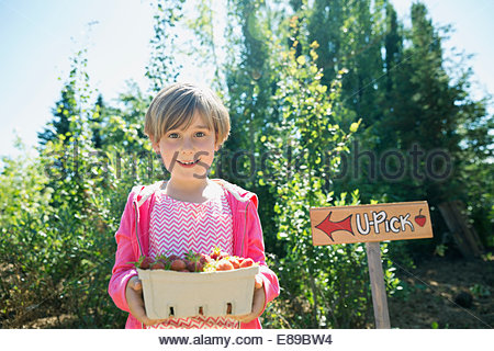 Portrait of smiling girl holding fresh picked strawberries