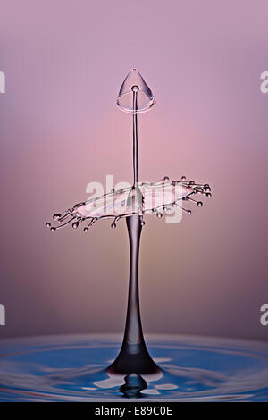 A tall water drop rebounds from a pool of water colliding with other drops forming a water sculpture. Stock Photo