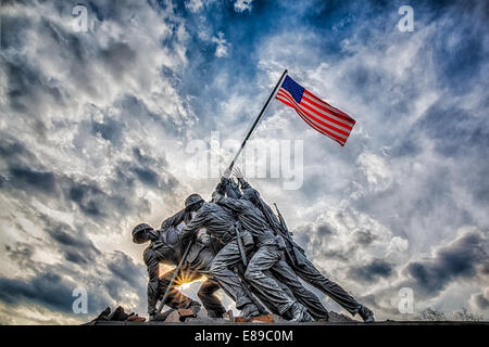 The Marine Corps War Memorial also called the Iwo Jima Memorial in Arlington, Virginia, with dramatic storm clouds in the background and a starburst at sundown. Stock Photo