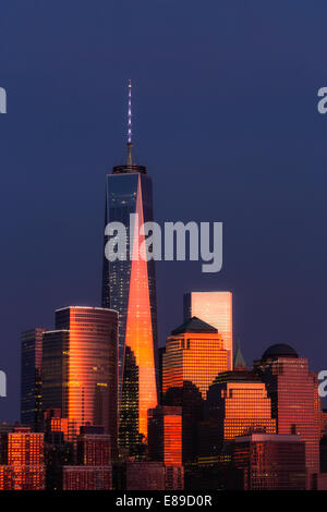 One World Trade Center commonly referred to as the Freedom Tower and other Financial District skyscrapers are bathed in golden light during the last light at sunset. Stock Photo
