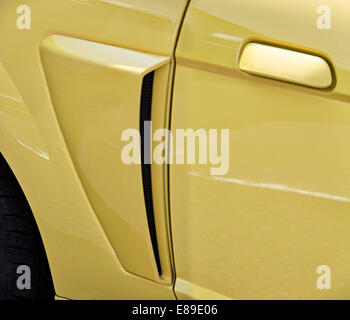 Side view of emblem, detail, tire and door of a yellow 1967 Chevrolet Camaro. Stock Photo