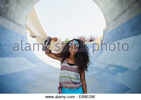 Portrait of teenage girl holding skateboard on ramp