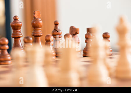 Wooden chess pieces facing off, across the games board during a match Stock Photo