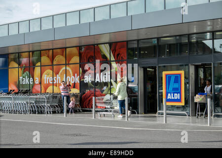 Customers & shopping carts outside German discount supermarket, Aldi in Swindon, Wiltshire, UK