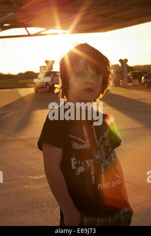 Boy standing at gas station at sunset Stock Photo