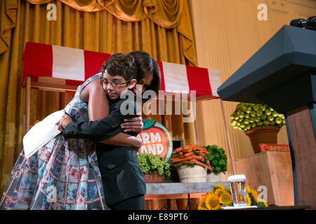 First Lady Michelle Obama hugs Braeden Mannering, the 2013 Kids' State Dinner winner from Delaware, after he introduced her at the Kids' State Dinner in the East Room of the White House, July 18, 2014 Stock Photo