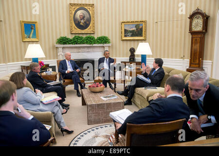 Chief of Staff Denis McDonough, right, confers with Ben Rhodes, Deputy National Security Advisor for Strategic Communications, as President Barack Obama and Vice President Joe Biden receive the Presidential Daily Briefing in the Oval Office, July 18, 2014 Stock Photo