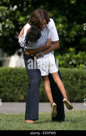 First Lady Michelle Obama hugs a child during a Drink Up event on the South Lawn of the White House, July 22, 2014. (Official Wh Stock Photo