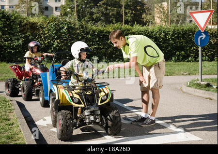 Tutor explaining quadbike to boy on driver training area Stock Photo