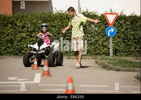 Tutor and girl with quadbike on driver training area Stock Photo