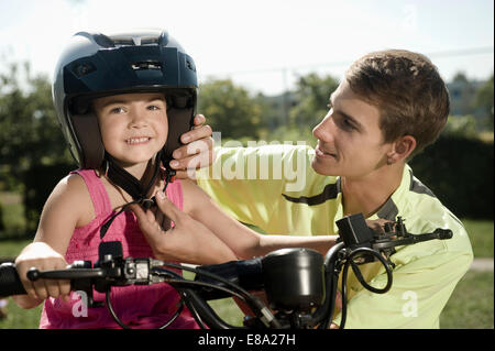 Tutor assisting girl with helmet on driver training area Stock Photo