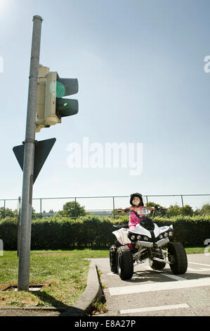 Girl with quadbike waiting at traffic light on driver training area Stock Photo
