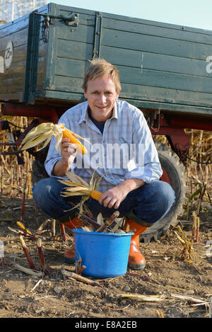 Farmer with corn harvest  in front of tractor, Bavaria, Germany Stock Photo