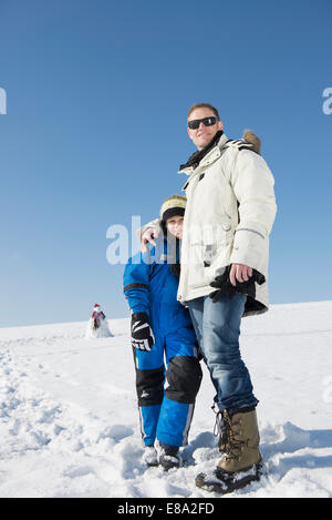 Father and son standing on snow, smiling, Bavaria, Germany Stock Photo