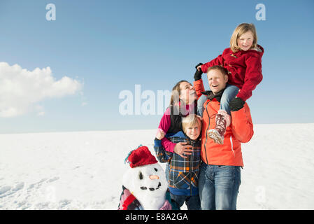 Family with snowman, smiling, Bavaria, Germany Stock Photo