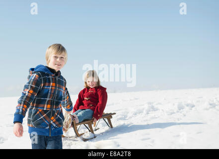 Boy pulling girl on sledge, Bavaria, Germany Stock Photo