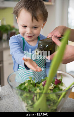 Boy helping mother in preparing salad, close up Stock Photo