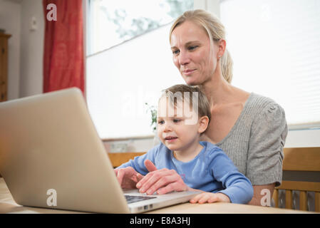 Mother and son using laptop, smiling Stock Photo