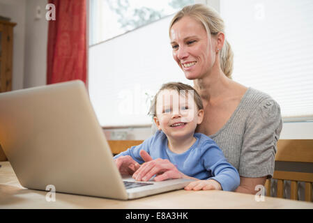 Mother and son using laptop, smiling Stock Photo