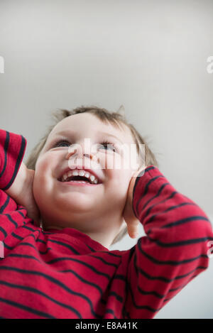 Boy covering ears, smiling Stock Photo