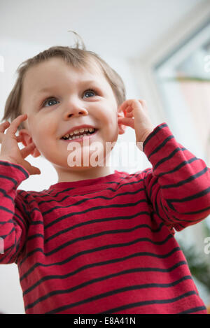 Boy with fingers in ears, smiling Stock Photo