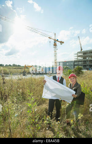 Architects with construction plan inspecting site Stock Photo