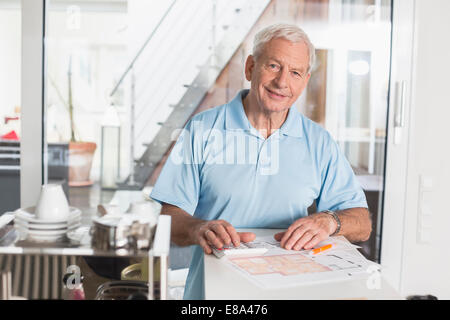 Smiling senior man using calculator at home Stock Photo