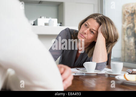Couple with construction plans sitting at table Stock Photo