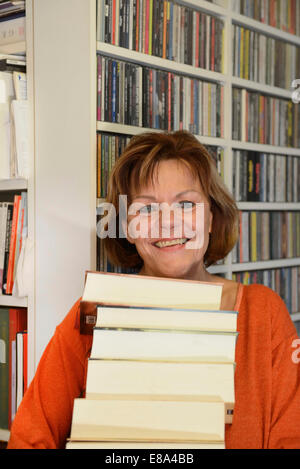 Senior woman with stack of books, smiling, portrait Stock Photo