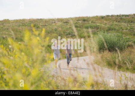 Mature couple running on field in summer Stock Photo
