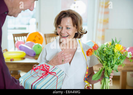 Senior man hand over present to woman on birthday, smiling Stock Photo