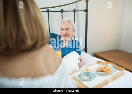 Couple having breakfast in bed, smiling Stock Photo