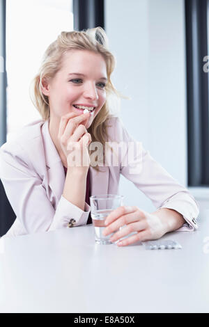 businesswoman with headache taking tablet Stock Photo