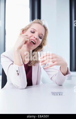 businesswoman with headache taking tablet Stock Photo