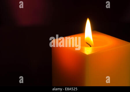 The yellow candle burning in the dark Stock Photo