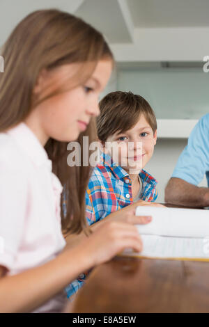 Children doing homework with their grandfather Stock Photo