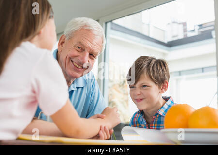 Children doing homework with their grandfather Stock Photo