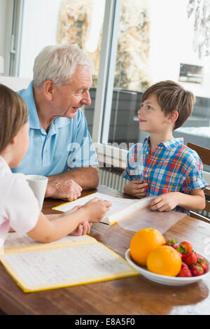 Children doing homework with their grandfather Stock Photo