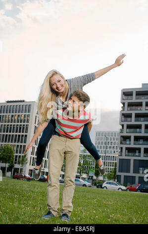 Teenage boy giving piggyback ride to teenage girl, smiling Stock Photo
