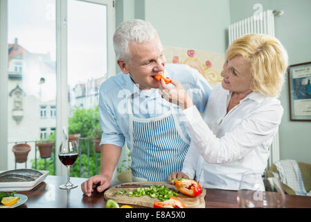 Mature woman feeding food to mature man, smiling Stock Photo
