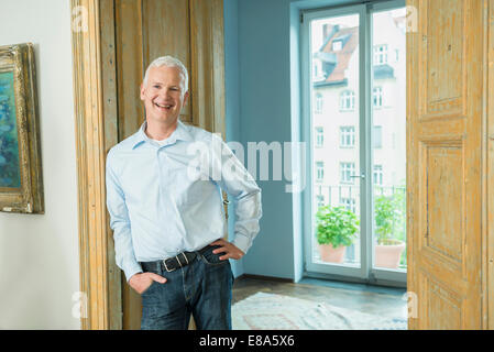 Portrait of mature man leaning against door, smiling Stock Photo