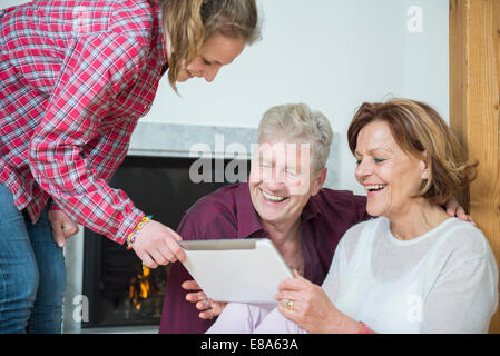 Granddaughter showing something on digital tablet to her grandparents, smiling Stock Photo