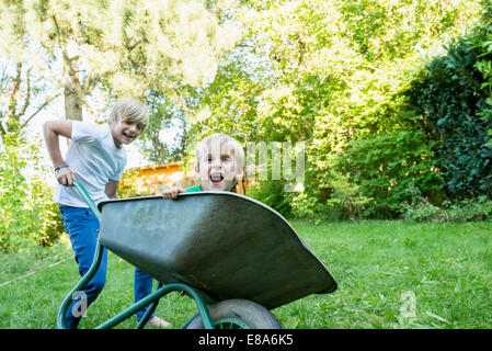 Two brothers playing with wheelbarrow in the garden Stock Photo