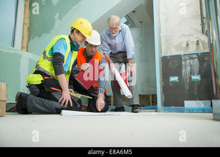 Architect and two construction workers at construction site of new building Stock Photo