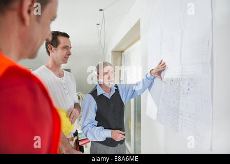 Architect and two construction workers at construction site of new building Stock Photo