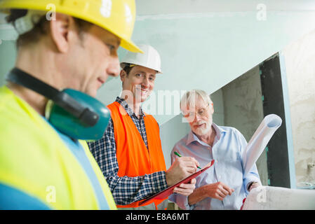 Architect and two construction workers at construction site of new building Stock Photo