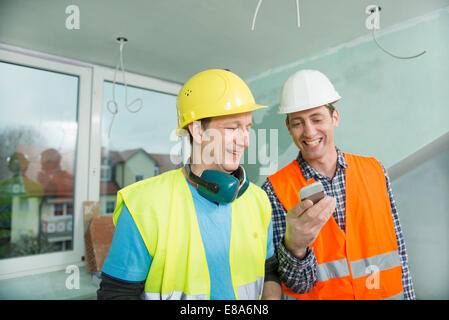 Two construction workers with smartphone at construction site of new building Stock Photo